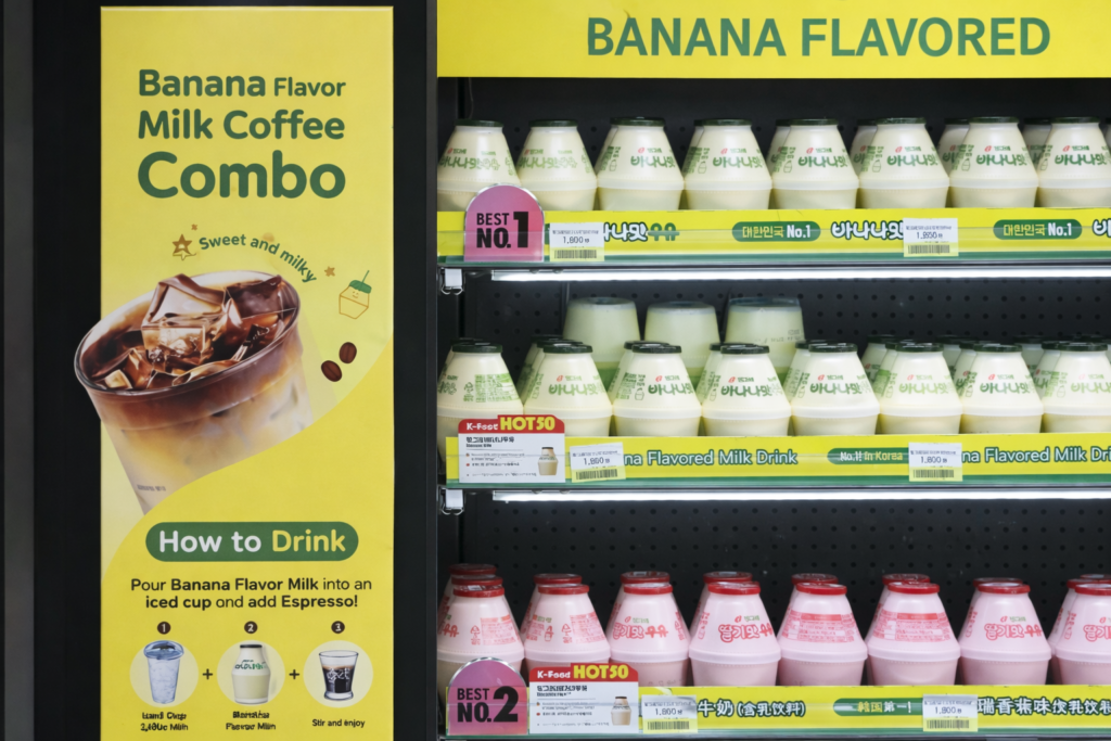 Close-up of Korean banana milk bottles in a convenience store with a promotional combo sign