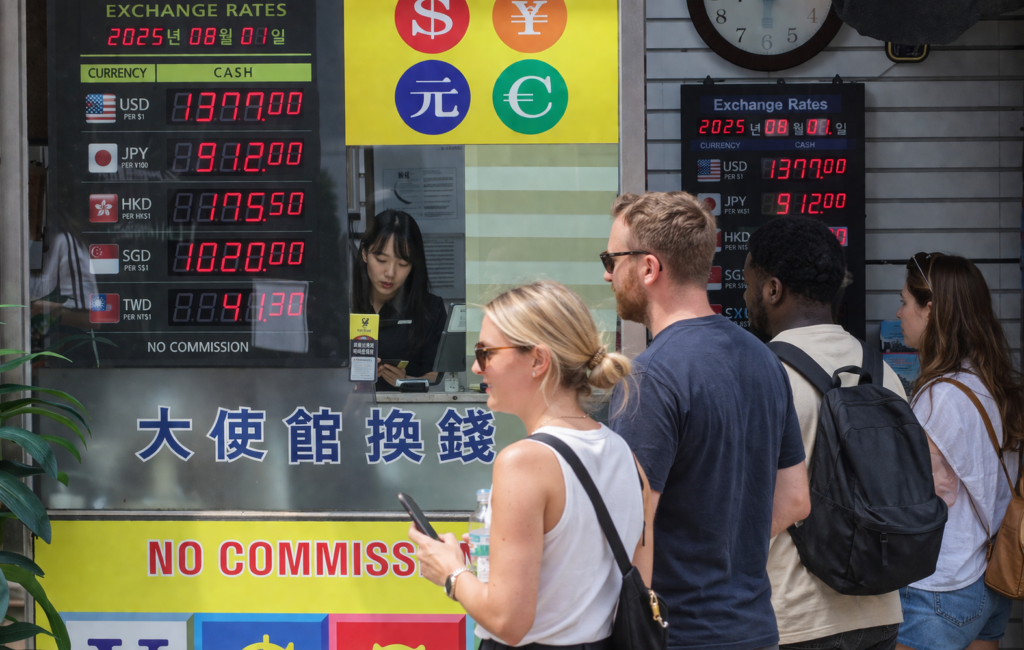 Foreign tourists exchanging money at a busy Myeongdong exchange office in Seoul with Korean staff inside